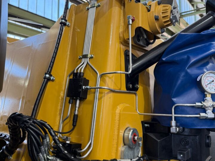 Lubrication lines routed between an excavator cab and boom