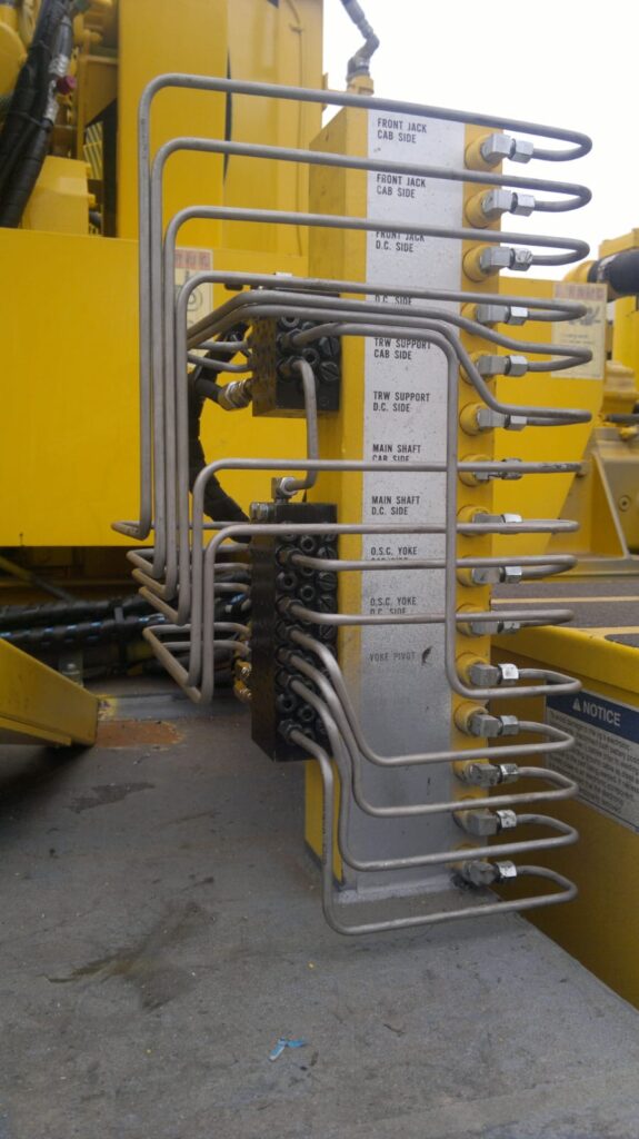 Fanned stainless steel tube runs from a lubrication manifold